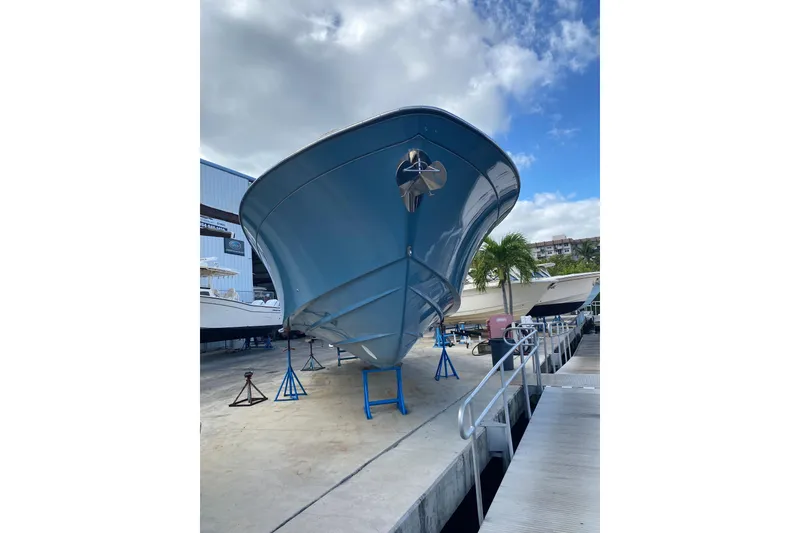 Slide: The Image of 2021 Grady-White Canyon 376 boat on stands, dockside view under cloudy sky. - 2