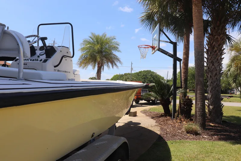 Slide: The Image of 2001 Maverick 21 Master Angler boat on trailer near palm trees and basketball hoop. - 3