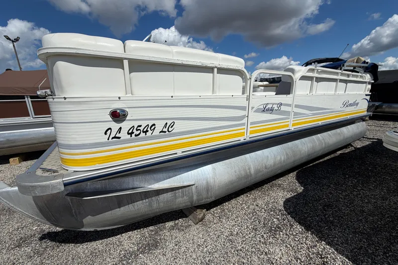 The Image of 2004 Bentley Pontoons 200 CRUISE pontoon boat with white and yellow accents, parked outdoors. - 1