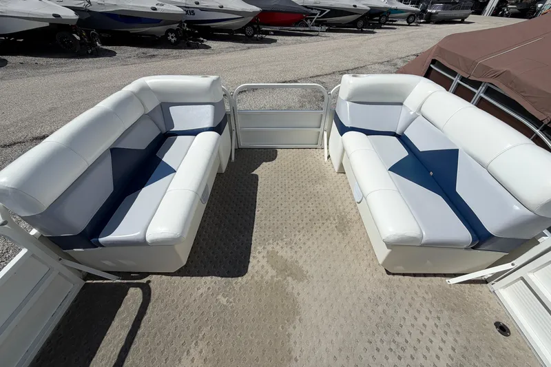 Slide: The Image of 2004 Bentley Pontoons 200 CRUISE interior with white and blue seating, docked among other boats. - 10
