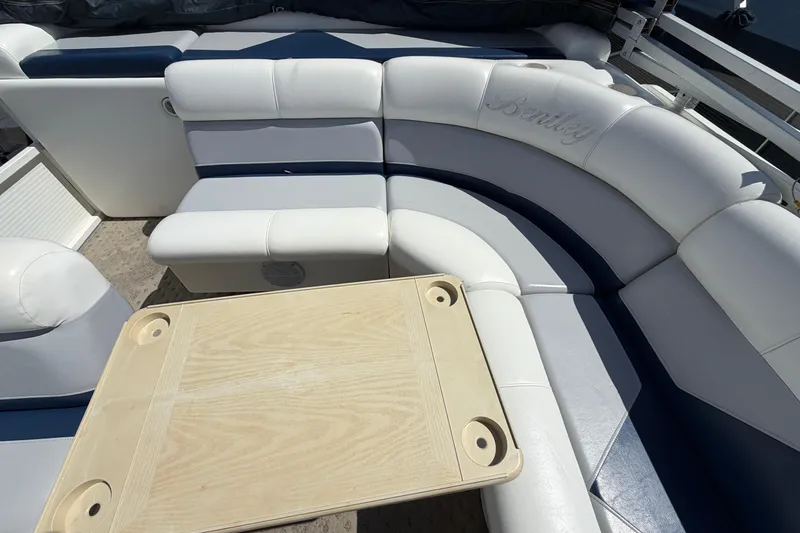Slide: The Image of 2004 Bentley Pontoons 200 CRUISE interior with white and blue seating and a wooden table. - 12