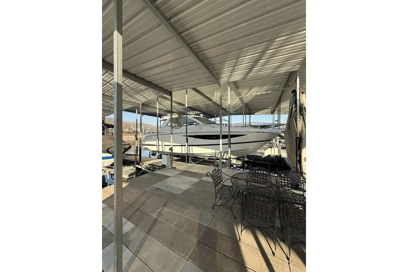 Slide: The Image of 2016 Cobalt A40 boat docked under covered marina with patio furniture nearby. - 7