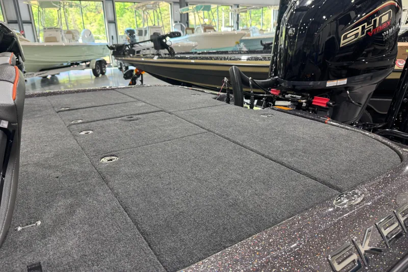 Slide: The Image of 2026 Skeeter ZXE20 boat interior with carpeted deck and powerful engine in showroom. - 8