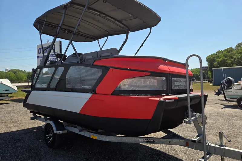 Slide: The Image of 2024 Sea-Doo Switch Cruise 18 pontoon boat on trailer, featuring a red and black design. - 2