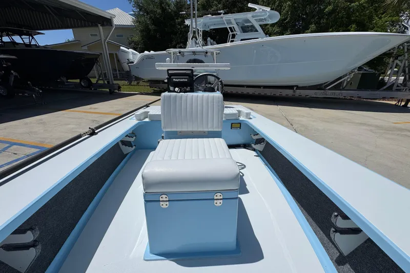 Slide: The Image of 2016 Hell's Bay Marquesa boat interior with seating and steering console in a marina setting. - 25