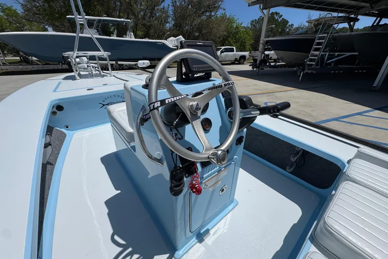 Slide: The Image of 2016 Hell's Bay Marquesa boat interior with steering wheel and seating, parked outdoors. - 28