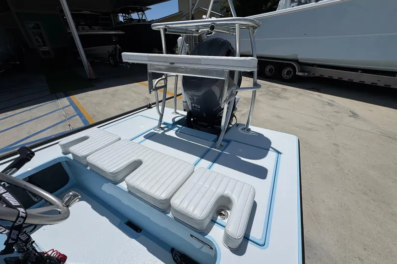 Slide: The Image of 2016 Hell's Bay Marquesa boat with cushioned seating and motor, parked on concrete. - 31