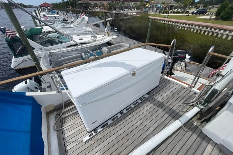 Slide: The Image of 1979 Albin 36 Trawler docked, featuring spacious deck with storage box and scenic marina view. - 16