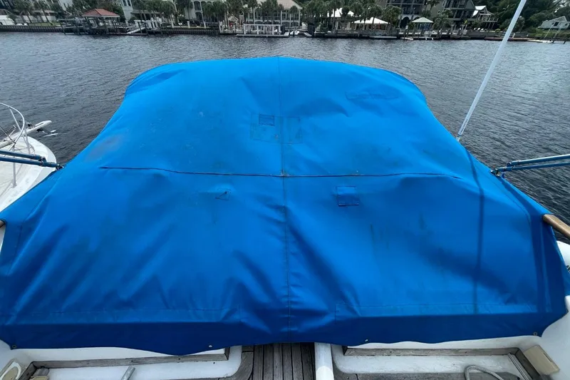 Slide: The Image of 1979 Albin 36 Trawler with blue cover, docked by waterfront homes. - 17