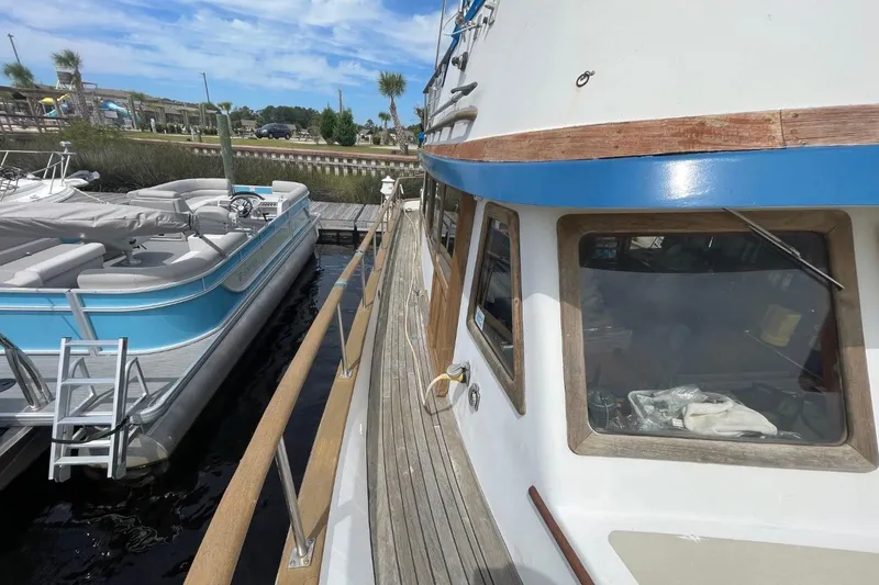 Slide: The Image of 1979 Albin 36 Trawler docked beside a blue pontoon boat under a clear sky. - 4