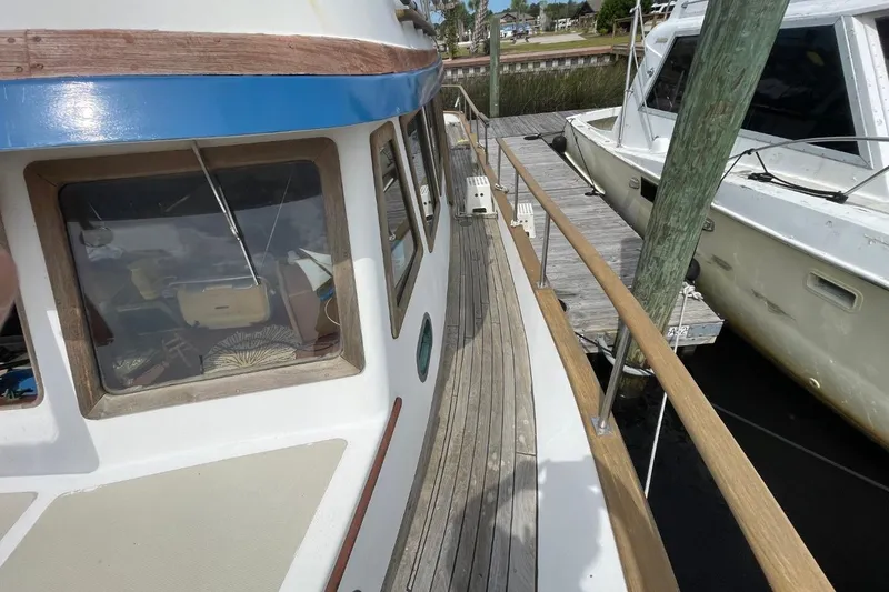 Slide: The Image of 1979 Albin 36 Trawler docked, showcasing wooden deck and cabin windows. - 5