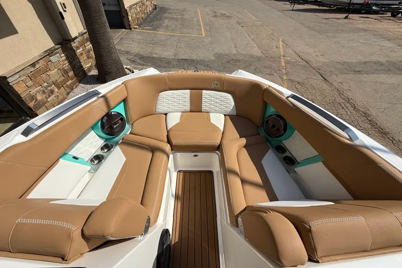 Slide: The Image of 2020 MasterCraft X22 boat interior with tan and white seating, teal accents, and cup holders. - 13