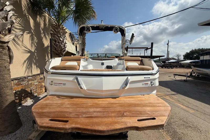 Slide: The Image of 2020 MasterCraft X22 boat with wooden deck, parked outdoors under a sunny sky. - 6