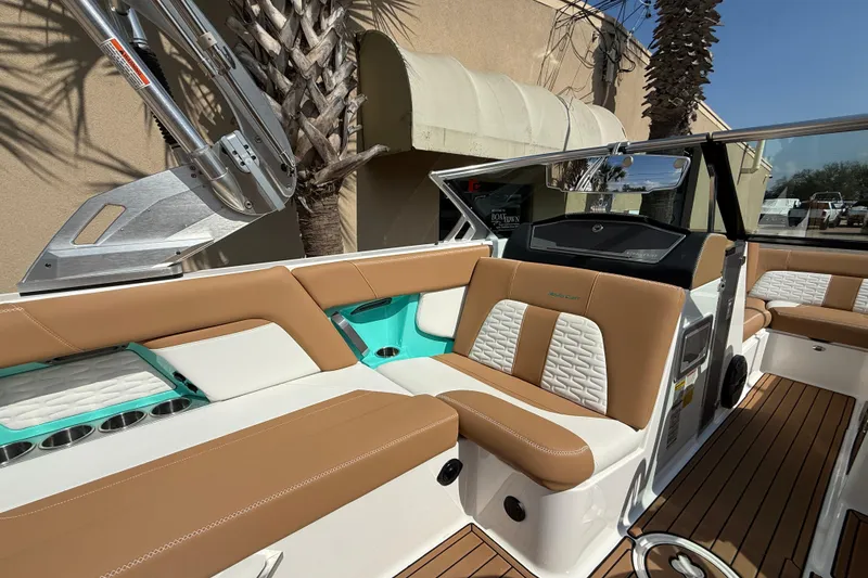 Slide: The Image of 2020 MasterCraft X22 boat interior with tan and white seating, teal accents, and wood flooring. - 9