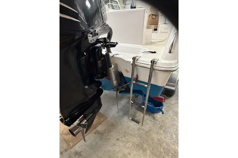 Slide: The Image of 2002 Pro-Line 260 Walkaround boat with outboard motor and ladder in a garage setting. - 13