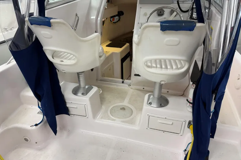 Slide: The Image of 2002 Pro-Line 260 Walkaround boat interior with white seats and blue curtains. - 25