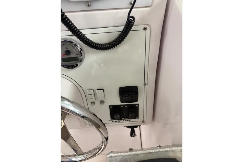 Slide: The Image of Control panel of a 2002 Pro-Line 260 Walkaround boat, featuring switches and a steering wheel. - 35
