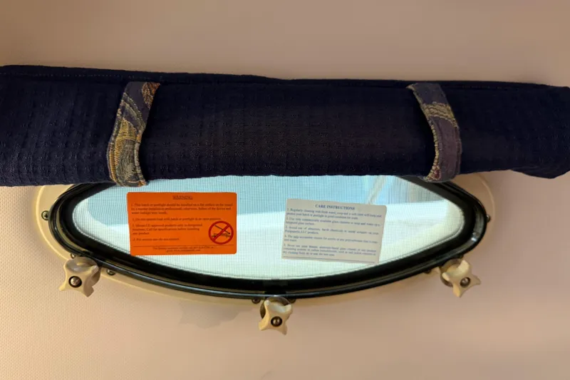 Slide: The Image of Porthole window with rolled towel and warning labels on a 2002 Pro-Line 260 Walkaround boat. - 40