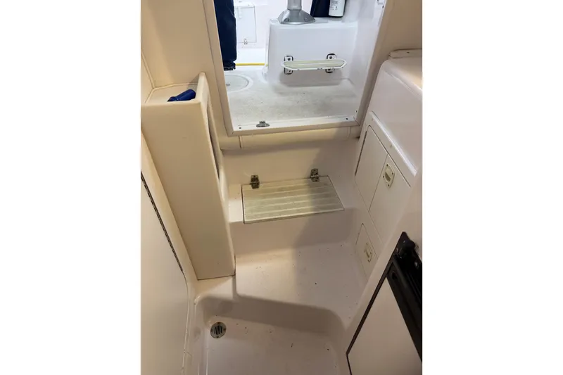 Slide: The Image of Interior of a 2002 Pro-Line 260 Walkaround boat, featuring storage compartments and a step. - 45