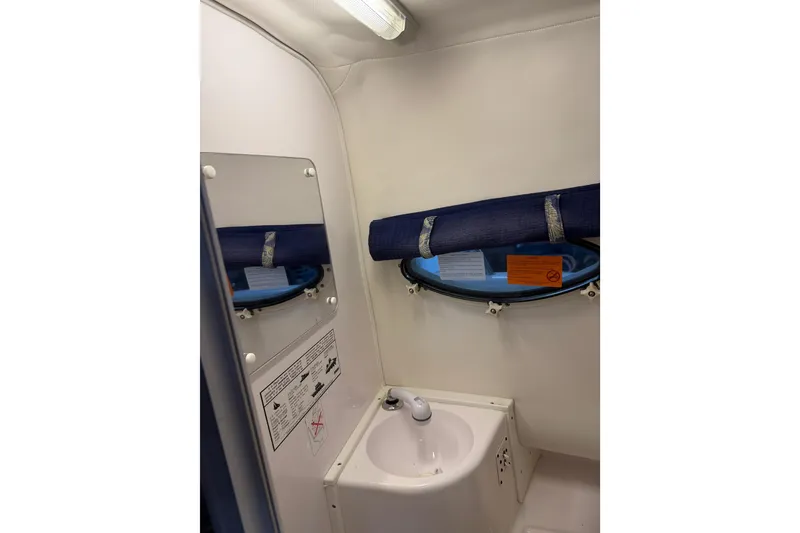 Slide: The Image of 2002 Pro-Line 260 Walkaround boat bathroom with sink, mirror, and porthole window. - 47