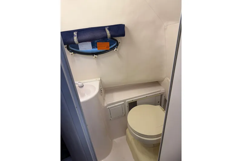 Slide: The Image of Compact bathroom in 2002 Pro-Line 260 Walkaround boat, featuring toilet and sink. - 49