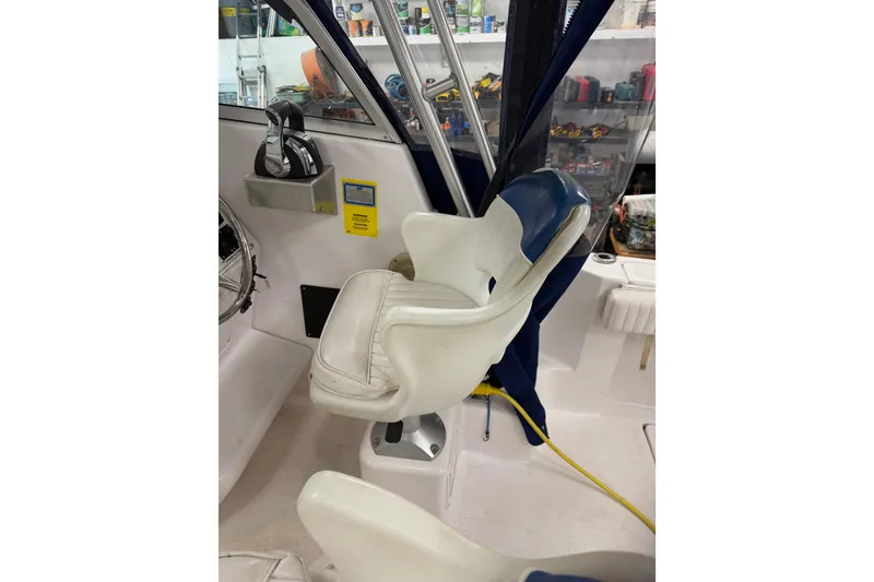 Slide: The Image of Captain's chair in 2002 Pro-Line 260 Walkaround boat cockpit, featuring steering controls. - 62
