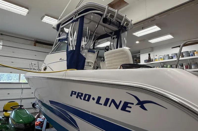 Slide: The Image of 2002 Pro-Line 260 Walkaround boat in a garage, showcasing sleek design and branding. - 7