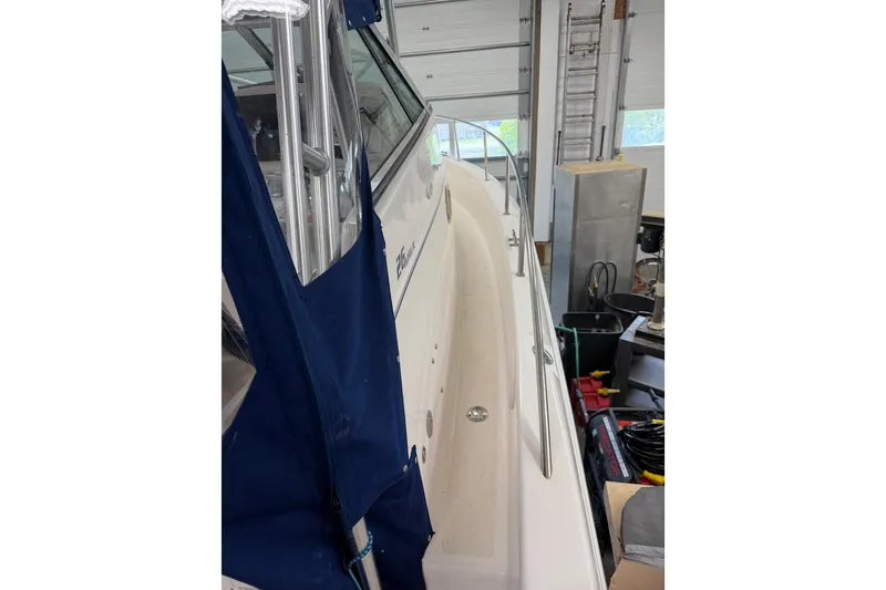 Slide: The Image of 2002 Pro-Line 260 Walkaround boat in garage, side view with blue cover. - 9