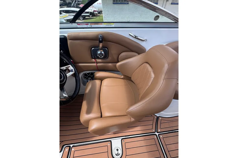 Slide: The Image of 2025 Crownline Eclipse E235 boat interior with tan leather seat and wood-style flooring. - 21