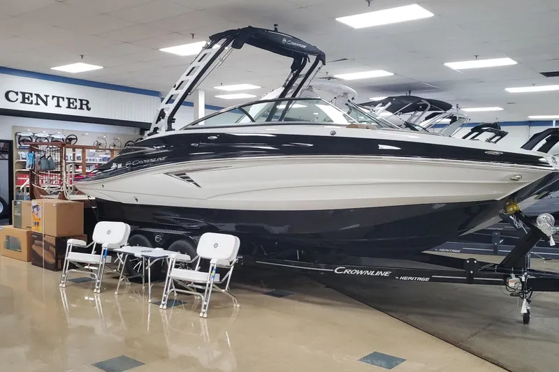 Slide: The Image of 2025 Crownline Eclipse E235 boat displayed indoors with chairs and boxes nearby. - 3