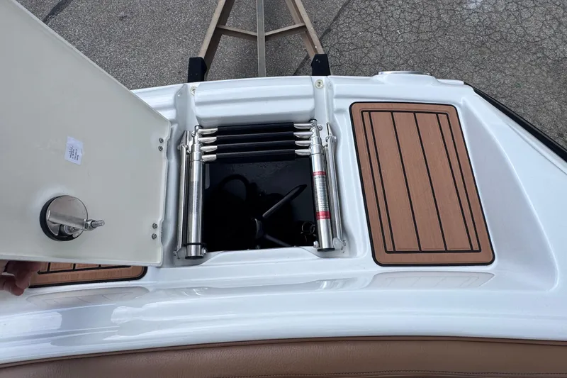 Slide: The Image of 2025 Crownline Eclipse E235 boat with open storage compartment and wooden deck panels. - 32