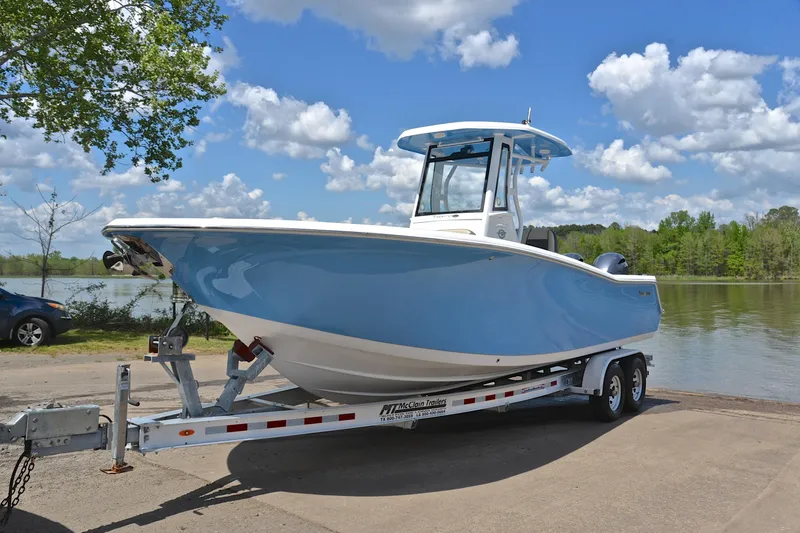 Slide: The Image of 2021 Tidewater 256 CC Adventure boat on trailer by a lake under blue sky. - 11