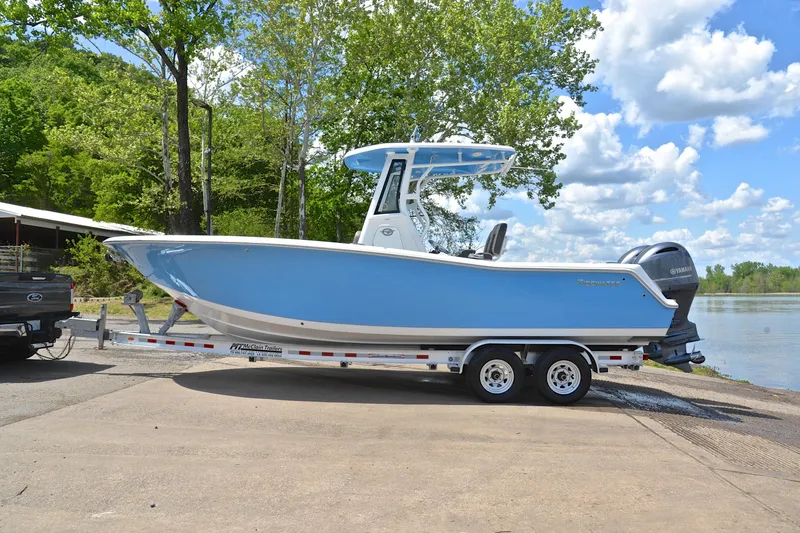 Slide: The Image of 2021 Tidewater 256 CC Adventure boat on trailer by a lake. - 12