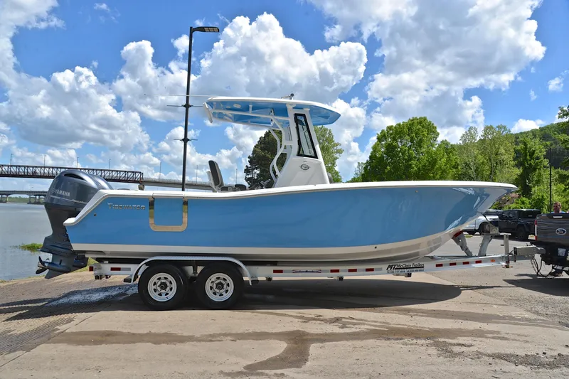 Slide: The Image of 2021 Tidewater 256 CC Adventure boat on trailer, blue hull, parked near river. - 16