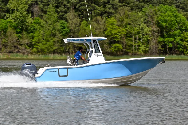 Slide: The Image of 2021 Tidewater 256 CC Adventure boat cruising on a lake with lush green forest backdrop. - 3