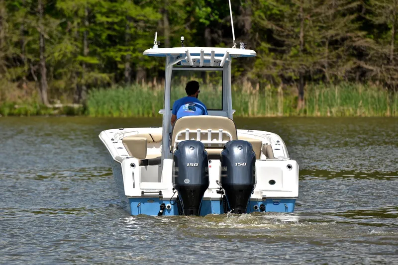 Slide: The Image of 2021 Tidewater 256 CC Adventure boat cruising on a calm lake with dual engines. - 9