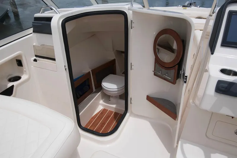 Slide: The Image of Manufacturer Provided Image: 2017 Grady-White Freedom 235 boat interior with a compact marine toilet and wooden accents. - 16