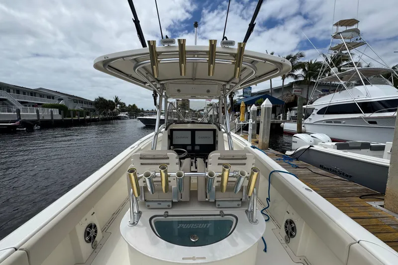 Slide: The Image of 2006 Pursuit 3480 Center Console boat docked at marina, featuring fishing rod holders. - 3