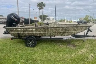 Slide: The Image of 2026 Crestliner 1760 Retriever SC boat on trailer, camo design, parked on grass. - 5