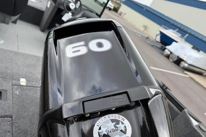 Slide: The Image of 2026 Crestliner 1650 Kodiak boat with a 60 HP outboard motor, parked outdoors. - 20