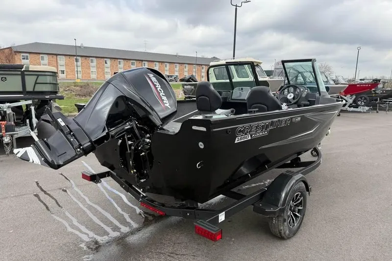Slide: The Image of 2026 Crestliner 1650 Kodiak boat with Mercury engine on trailer, parked outdoors. - 4