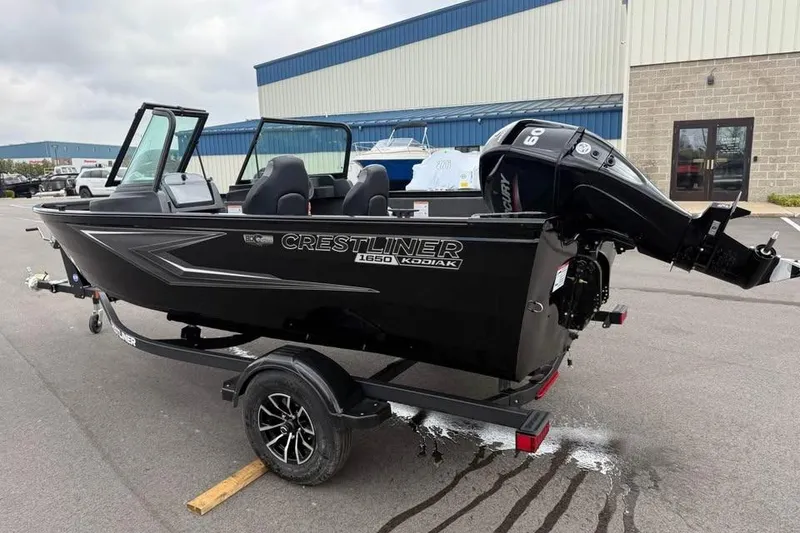 Slide: The Image of 2026 Crestliner 1650 Kodiak boat with outboard motor on trailer, parked outdoors. - 5