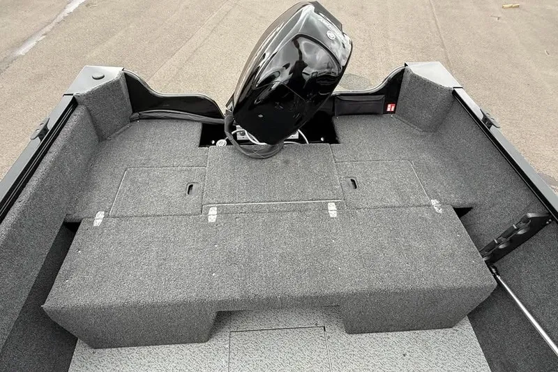 Slide: The Image of 2026 Crestliner 1650 Kodiak boat interior with motor, featuring spacious carpeted deck. - 7