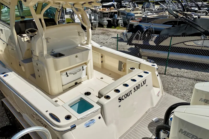 Slide: The Image of 2026 Scout 330 LXF boat with spacious deck and modern amenities in a marina setting. - 18