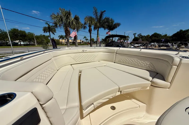 Slide: The Image of Luxurious seating on 2026 Scout 330 LXF boat with palm trees and flags in background. - 25