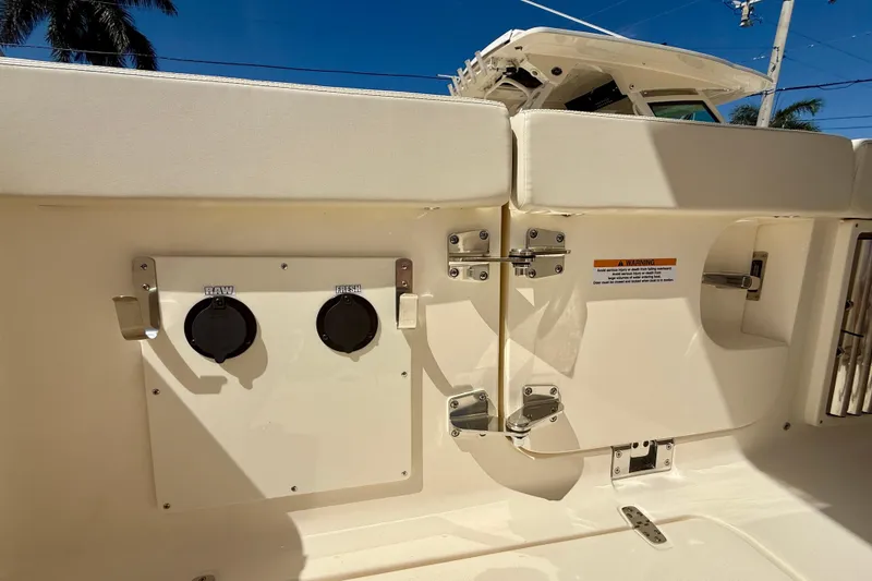 Slide: The Image of 2026 Scout 330 LXF boat deck with water access panel under clear blue sky. - 42
