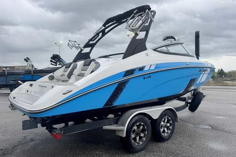 Slide: The Image of 2021 Yamaha Boats 212X in blue on a trailer, under cloudy skies. - 14