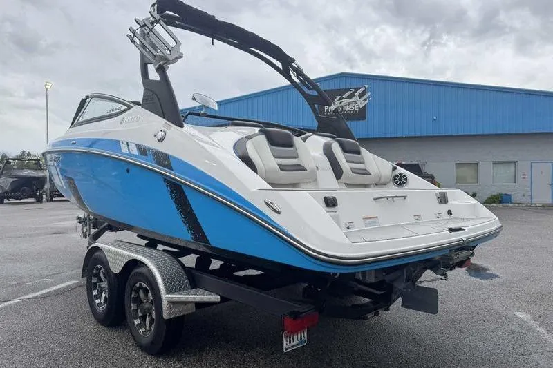 Slide: The Image of 2021 Yamaha Boats 212X in blue, parked on a trailer outside a blue building. - 16