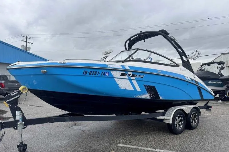 Slide: The Image of 2021 Yamaha Boats 212X in blue, parked on a trailer in a lot. - 3