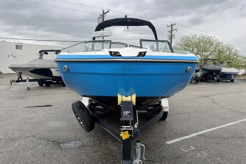 Slide: The Image of 2021 Yamaha Boats 212X in blue on trailer, parked outdoors. - 4